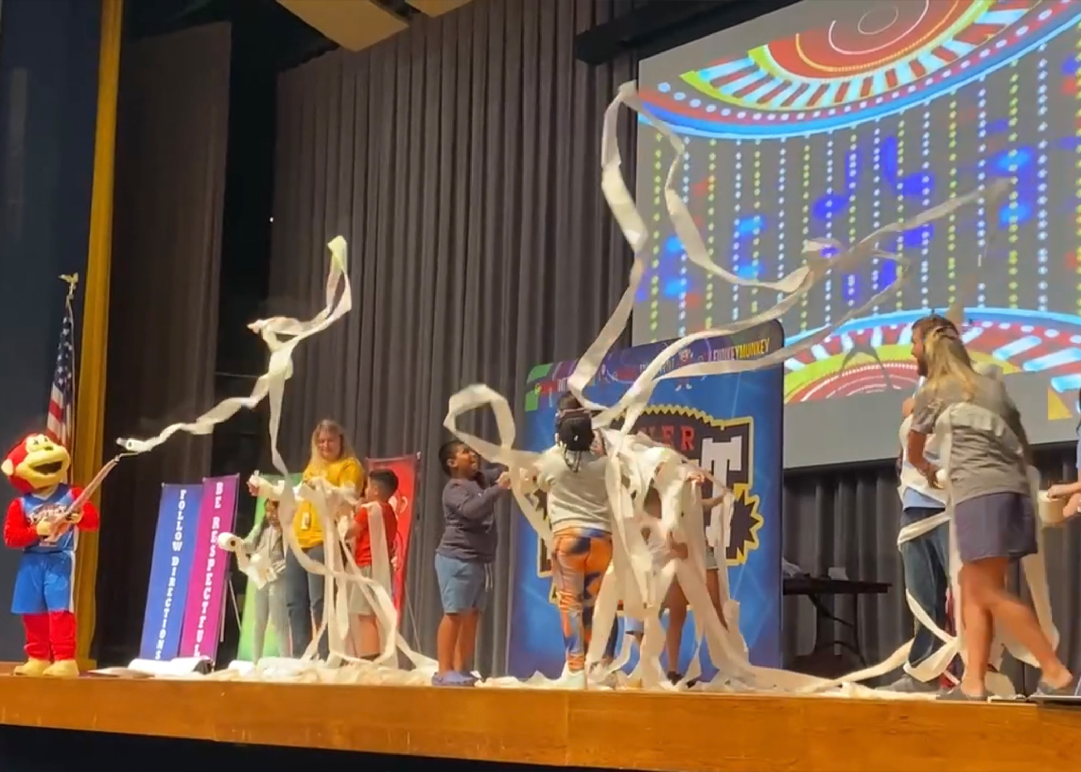 Students and Funkey Munkey mascot participating in a high-energy interactive game on stage